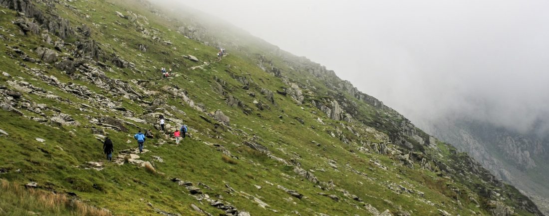 Walkers ascend into fog on Snowdon / Yr Wyddfa by the Snowdon Ranger path, in May 2017.